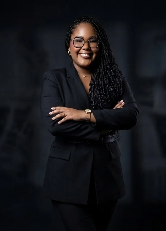 Advogada Samara Lesli, sorrindo, de blazer preto e braços cruzados.
